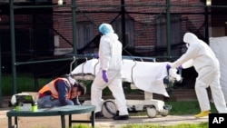 Medical personnel transport a body from a refrigerated container at Kingsbrook Jewish Medical Center, April 8, 2020, in the Brooklyn borough of New York. 