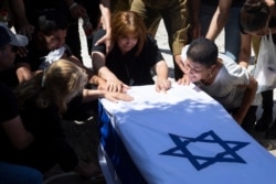 Relatives of Israeli soldier Omer Tabib, 21, mourn during his funeral at the cemetery in the northern Israeli town of Elyakim, May 13, 2021.