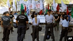 Police officers stand in front of the protesters during an anti-bailout protest outside of the Cyprus parliament in Nicosia, April 30, 2013.