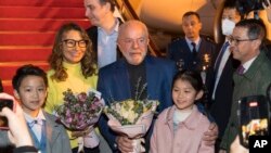 En esta imagen publicada por la Agencia de Noticias Xinhua, el presidente de Brasil, Luiz Inácio Lula da Silva y la primera dama Rosangela Silva reciben flores de niños en el Palacio de los Niños de Shanghái el miércoles 12 de abril de 2023.