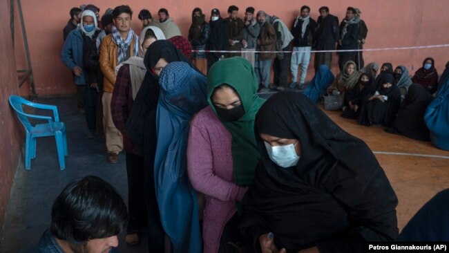 People wait to receive money at a center organized by the World Food Program in Kabul, Afghanistan on November 17, 2021. With the U.N. warning millions are near-famine, the WFP has greatly increased direct aid to families. (AP Photo/Petros Giannakouris)