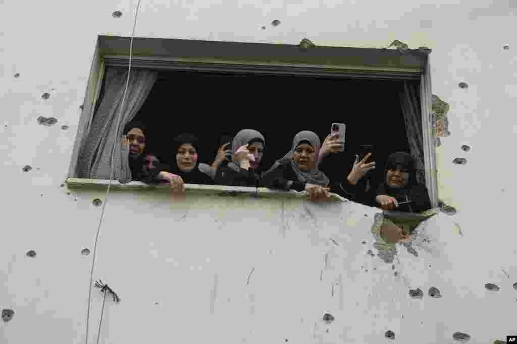 Mourners watch the funeral of Palestinian men who were killed during an Israeli military operation, from a building damaged with bullet holes, in Jenin, West Bank.