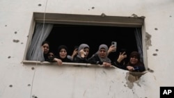 Mourners watch the funeral of Palestinian men who were killed during an Israeli military operation, from a building damaged with bullet holes, in Jenin, West Bank.