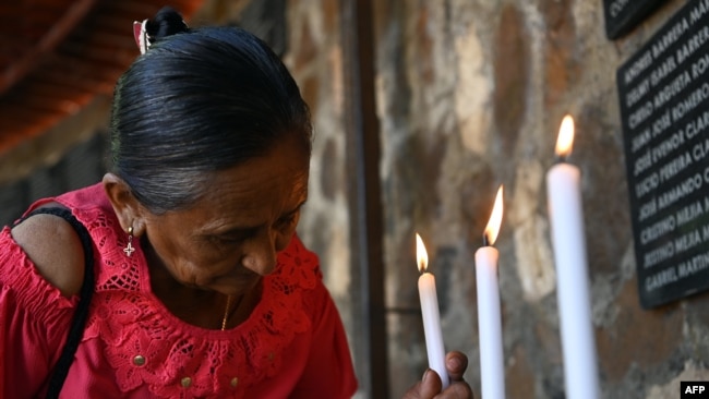 Una mujer enciende una vela en conmemoración de la masacre de El Mozote. Más de 75,000 personas fueron asesinadas o desaparecieron durante la guerra civil de El Salvador.