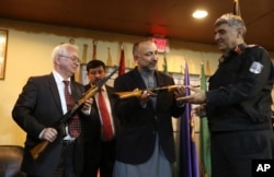 Russian Federation Ambassador Alexander Mantytskiy, left, hands over an AK-47 to Afghan National Security Adviser, Mohammad Hanif Atmar, center, at the International Kabul Airport, Feb. 24, 2016.