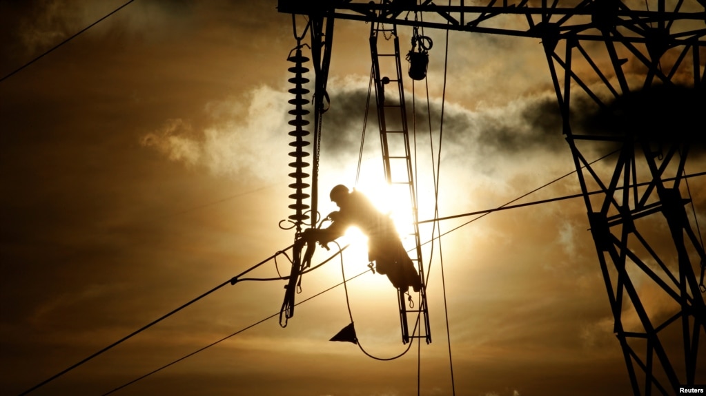 A technician works on an electricity pylon as part of maintenance of high-tension electricity power lines, during sunset in Roye, France, February 11, 2019. 