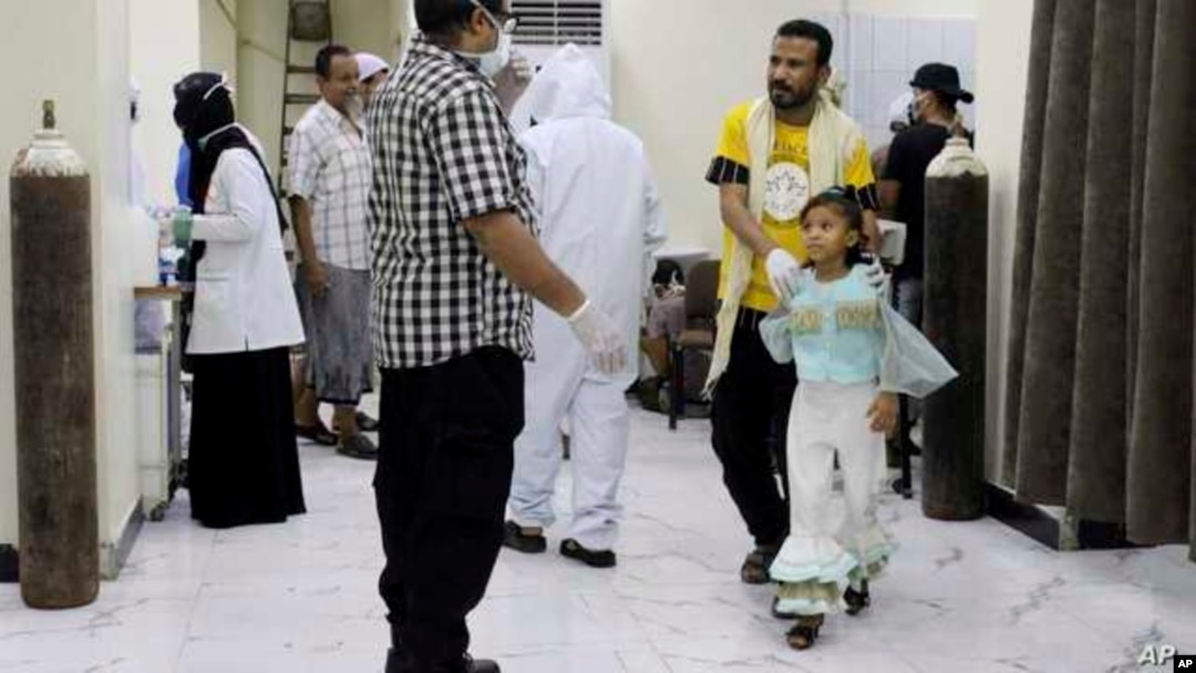 Yemeni medical workers wearing masks and protective gear talk to patients at hospital in Aden, where people have been dying by the dozens each day.