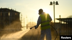 A worker sanitizes a street on the fourth day of an unprecedented lockdown across all of Italy imposed to slow the outbreak of coronavirus, in Milan, Italy, March 13, 2020. 