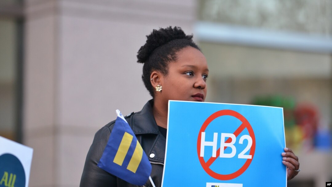 FILE - Cassandra Thomas of Human Rights Campaign holds a sign advocating the repeal of HB2 Dec. 7, 2016, in Charlotte, NC. 