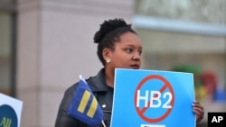 FILE - Cassandra Thomas of Human Rights Campaign holds a sign advocating the repeal of HB2 Dec. 7, 2016, in Charlotte, NC. 