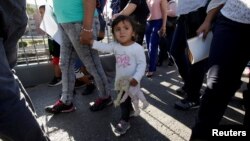 Migrant families from Mexico, fleeing violence, enter the United States to meet officers of the U.S. Customs and Border Protection to apply for asylum at Paso del Norte international border crossing bridge in Ciudad Juarez, June 20, 2018.