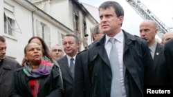  French Interior Minister Emmanuel Valls (R) and Justice Minister Christiane Taubira (L) visit the scene of a Roma squat in which a fire broke out in Lyon, France, May 13, 2013.
