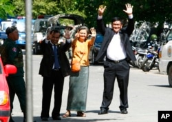 Cambodian lawmakers from the main opposition party of Cambodia National Rescue Party (CNRP), from right, Men Sothavrin, Mu Sochua and Keo Phirum gesture to make the number seven, the party's ballot number, as they are detained by authorities at Freedom Pa