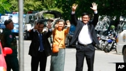 Cambodian lawmakers from the main opposition party of Cambodia National Rescue Party (CNRP), from right, Men Sothavrin, Mu Sochua and Keo Phirum gesture to make the number seven, the party's ballot number, as they are detained by authorities at Freedom Pa