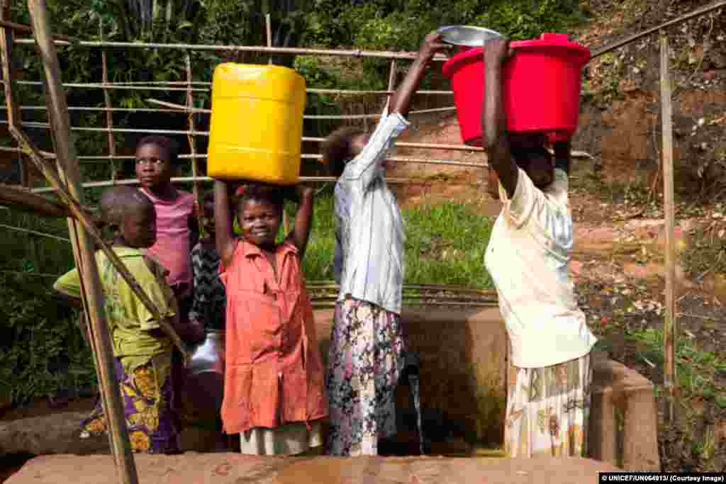 Mulheres e crianças vão abastecer-se de água num poço gerido pelo UNICEF emTshinyama, mna província congolesa do Kasai Oriental.