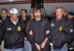 FILE - Tersangka perdagangan senjata Rusia Viktor Bout (tengah), dikawal ketat oleh petugas DEA dalam penerbangan dari Bangkok ke New York, 16 November 2010, disediakan oleh (DEA), (AP/ Drug Enforcement Administration (DEA))