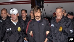 FILE - This Nov. 16, 2010 photo, provided by U.S. Drug Enforcement Administration (DEA), shows Viktor Bout, center, being led by DEA officers off a flight in New York before Bout's 2012 conviction in U.S. courts for illegal arms trafficking .