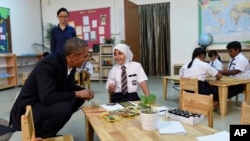 President Barack Obama listens to a girl while meeting with children during his tour to the Dignity for Children Foundation in Kuala Lumpur, Malaysia, Nov. 21, 2015. 