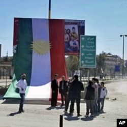 People stand in front of a Kurdish flag during a protest against Syria's President Bashar al-Assad and a celebration of Nowruz held by Qamishli's Kurdish community, March 21, 2012.
