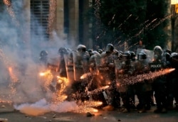 Firecrackers thrown by protesters explode in front of riot police amid clashes in the vicinity of the parliament in central Beirut on August 10, 2020.