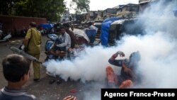 FILE - People react as a civic worker fumigates a slum area as a preventive measure against malaria and dengue ahead of monsoon in Mumbai, India, June 12, 2020.