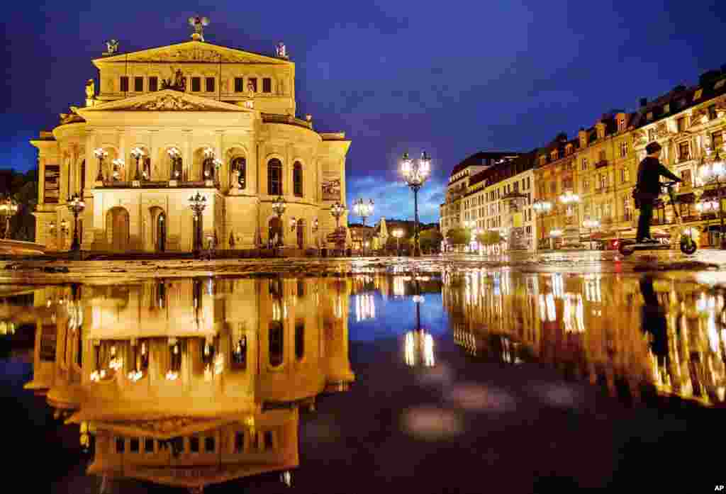 A Chinese tourist drives an E-scooter over the square in front of the Old Opera in Frankfurt, Germany.