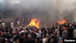 Người biểu tình đứng xem đồ đạc của người theo đạo Ky-tô bị đốt tại một khu vực ở Lahore, ngày 9/3/2013.