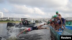 An athlete dives in on a false start in the men's Olympic triathlon at Odaiba Marine Park, Tokyo, Japan, July 26, 2021. 