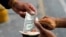 Un hombre cambia un billete de un dólar con el cobrador del autobús, que sostiene un fajo de billetes de Bolívar, en una parada de autobús frente a una estación de metro en Caracas, el 9 de marzo de 2021.