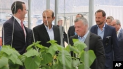 Jordan's King Abdaullah II and Norway's Crown Prince Haakon listen to a briefing, Sept. 7, 2017, during a visit of a new facility in Jordan’s Red Sea port city of Aqaba that produces crops from seawater, using clean energy.