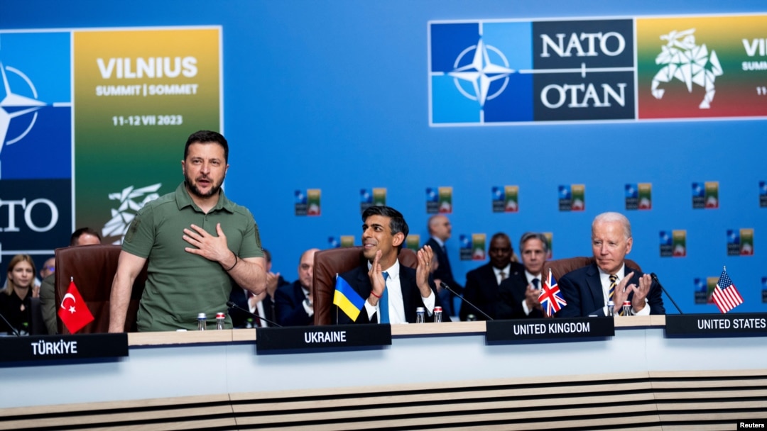 Президент Украины Владимир Зеленский принимает аплодисменты от глав стран НАТО, включая премьер-министра Великобритании Риши Сунака и президента США Джо Байдена, во время заседания Совета НАТО-Украина, на саммите НАТО в Вильнюсе, Литва, 12 июля 2023 г.