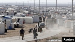 Syrian refugees walk at the Al Zaatari refugee camp in the Jordanian city of Mafraq, near the border with Syria, December 7, 2014.