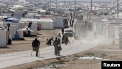 Syrian refugees walk at the Al Zaatari refugee camp in the Jordanian city of Mafraq, near the border with Syria, December 7, 2014.