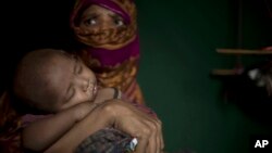 In this June 25, 2018, photo, "S" holds her baby boy as she sits in her shelter in Balukhali refugee camp in Bangladesh.