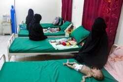 FILE - Women sit next to malnourished children lying on beds at a malnutrition treatment center in Yemen's war-ravaged western province of Hodeida, August 18, 2021.