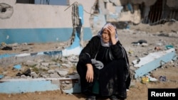 A woman rests next to a damaged building, as Palestinians arrive in Rafah after they were evacuated from Nasser Hospital in Khan Younis due to the Israeli ground operation, amid the ongoing conflict between Israel and Hamas, in the southern Gaza Strip, Feb. 15, 2024.