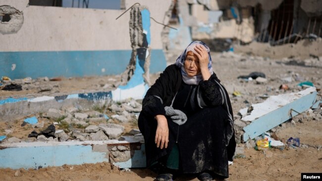 A woman rests next to a damaged building, as Palestinians arrive in Rafah after they were evacuated from Nasser Hospital in Khan Younis due to the Israeli ground operation, amid the ongoing conflict between Israel and Hamas, in the southern Gaza Strip, Feb. 15, 2024.