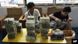 In this photo taken on Nov. 5, 2010, Myanmar men pack local banknotes in a Chinese-own gold shop in Mandalay, northern Myanmar. (AP Photo)