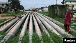 FILE - A girl walks on a gas pipeline running through Okrika community near Nigeria's oil hub city of Port Harcourt, Dec. 4, 2012. A new $3.5 billion East African Crude Oil Pipeline is projected to run 1,450 kilometers from the Uganda to Tanzania.