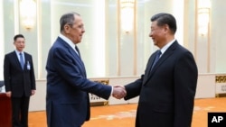 In this photo released by the Russian Foreign Ministry Press Service on April 9, 2024, Russian Foreign Minister Sergey Lavrov and Chinese President Xi Jinping shake hands during their meeting in Beijing, China.