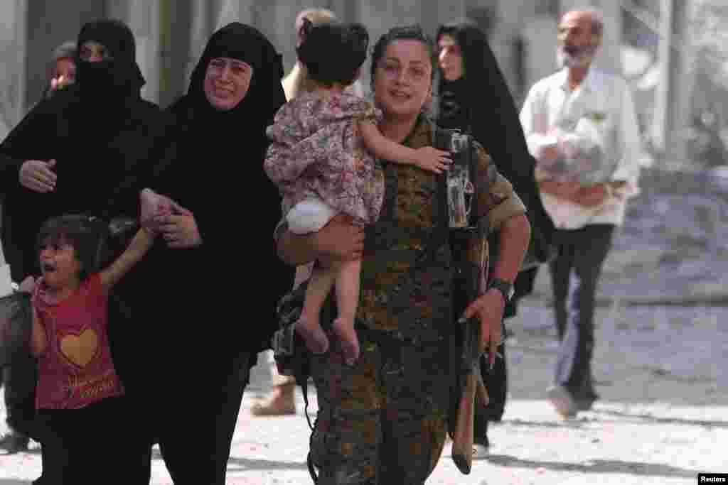 A Syria Democratic Forces (SDF) fighter helps civilians who were evacuated by the SDF from an Islamic State-controlled neighborhood of Manbij, in Aleppo Governorate, Syria, Aug. 12, 2016.