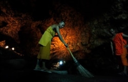FILE - A Buddhist monk sweeps up bat guano in a cave near Wat Khao Chong Phran Temple in Ratchaburi province, Thailand, September 14, 2009.