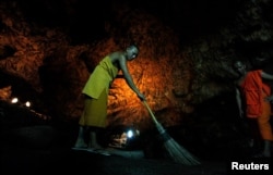 FILE - A Buddhist monk sweeps up bat guano in a cave near Wat Khao Chong Phran Temple in Ratchaburi province, Thailand, September 14, 2009.