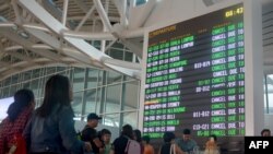 Para calon penumpang memeriks jadwal penerbangan di Bandara Ngurah Rai di Denpasar, Bali, yang sempat ditutup karena abu erupsi Gunung Agung, 29 Juni 2018.