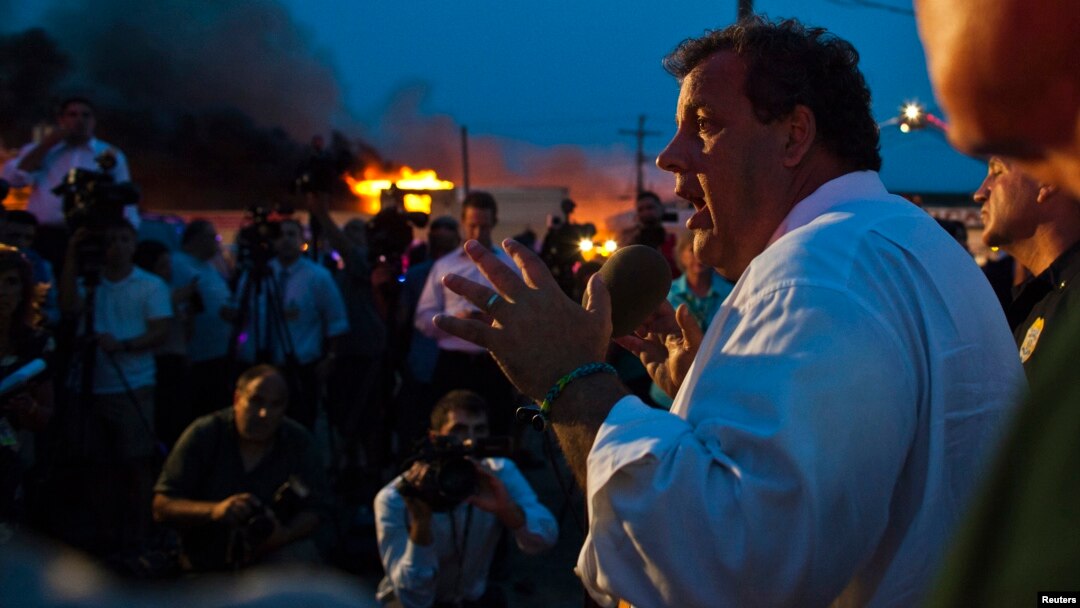 Gubernur New Jersey Chris Christie berbicara kepada media sementara regu pemadam kebakaran berusaha memadamkan api di Seaside Park, 12/9/2013. 
