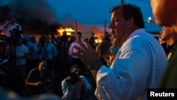 Gubernur New Jersey Chris Christie berbicara kepada media sementara regu pemadam kebakaran berusaha memadamkan api di Seaside Park, 12/9/2013. 