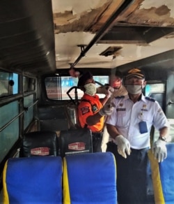 Para petugas melakukan penyemprotan disinfektan di dalam sebuah bus (VOA/Yudha).