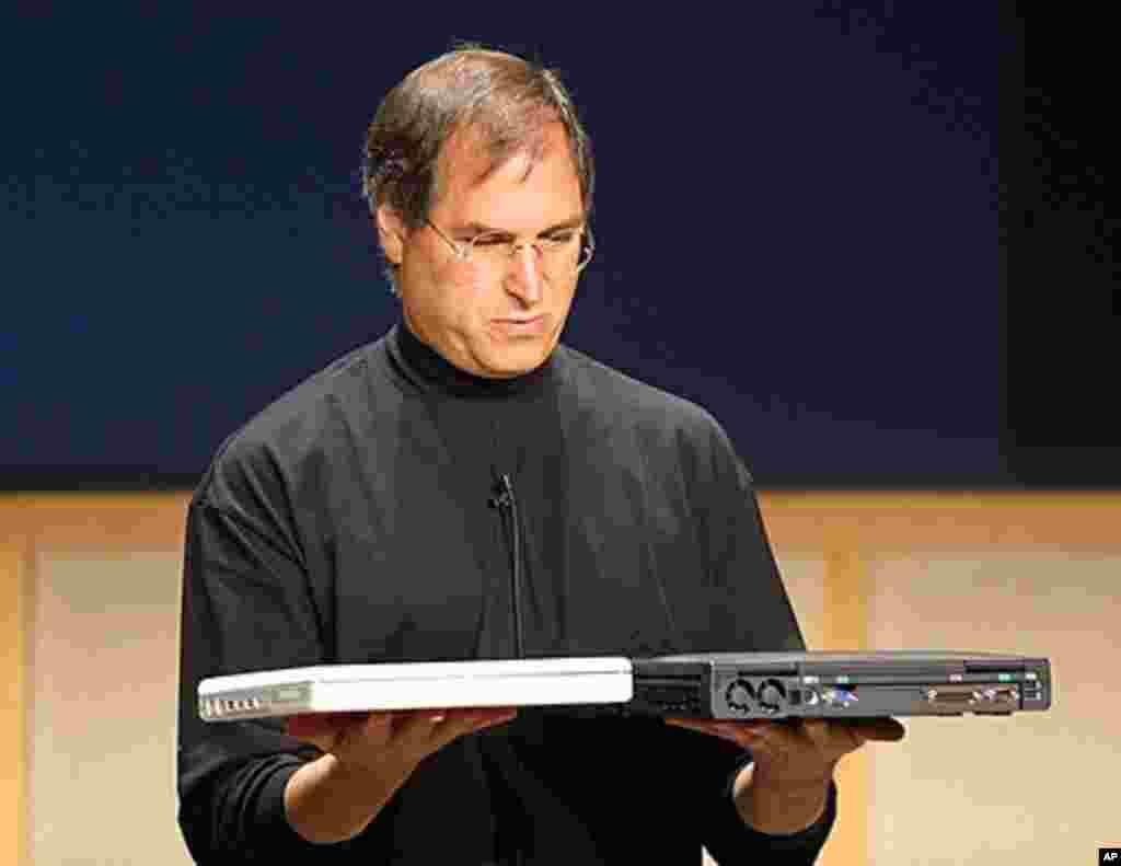 2001年5月1日：在加利福尼亚州库珀蒂诺举行的新闻发布会上，乔布斯手捧全新的苹果iBook笔记本电脑(4.9磅)和一个戴尔笔记本电脑，比较两者的重量。(AFP)