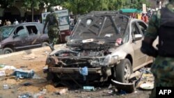 Military officers walk past scene of explosion in Kaduna, northern Nigeria, July 23, 2014.