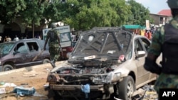 FILE - Military officers walk past scene of explosion in Kaduna, northern Nigeria.